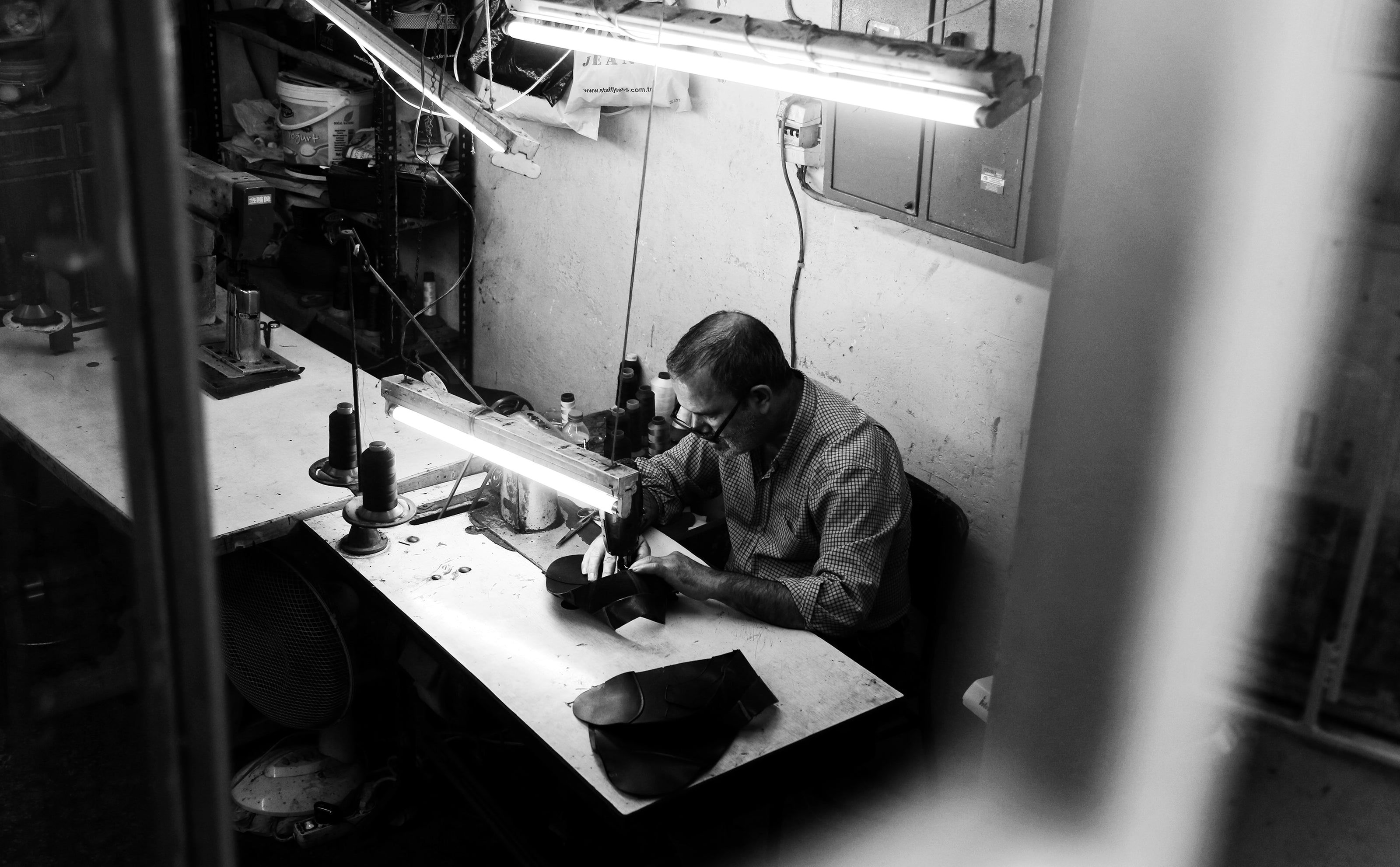 black-and-white-photo-of-a-person-sitting-by-sewing-machine